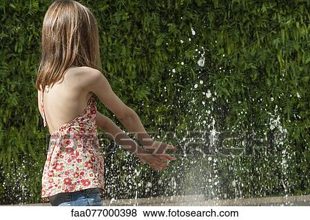 Girl playing in water in public fountain, rear view View Large Photo Image Stock Photo - Girl playing in water in public fountain, rear view. Fotosearch