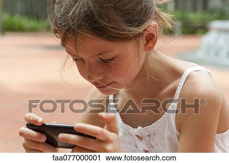 Stock Image - Girl playing with smartphone. Fotosearch