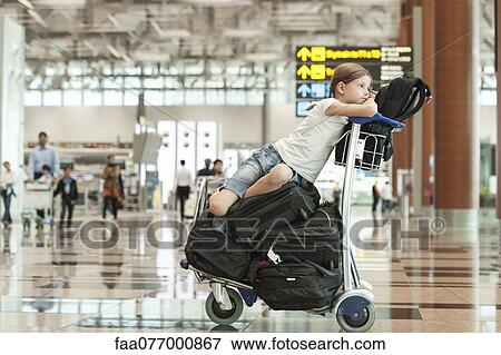 Girl sitting on top of luggage in airport View Large Photo Image Stock Photo - Girl sitting on top of luggage in airport. Fotosearch