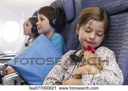 Girl sleeping on airplane holding stuffed toy View Large Photo Image Stock Image - Girl sleeping on airplane holding stuffed toy. Fotosearch