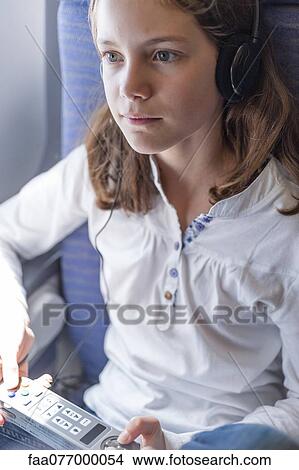 Girl using remote control to change channels on airplane View Large Photo Image Picture - Girl using remote control to change channels on airplane. Fotosearch