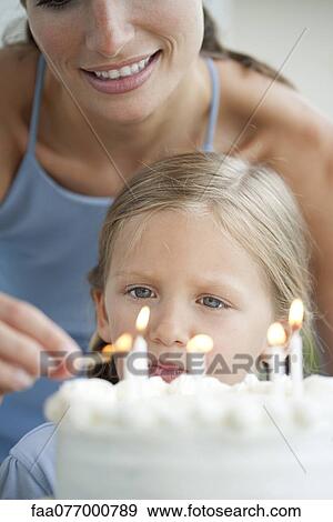 Girl watching as her mother lights candles on birthday cake View Large Photo Image Stock Photo - Girl watching as her mother lights candles on birthday cake. Fotosearch