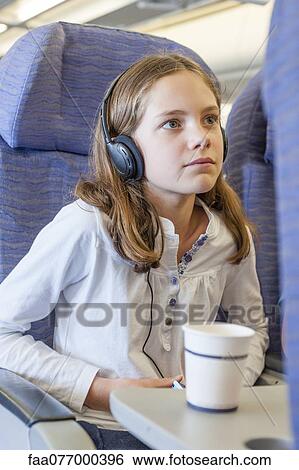 Girl watching movie with headphones on airplane View Large Photo Image Stock Photograph - Girl watching movie with headphones on airplane. Fotosearch