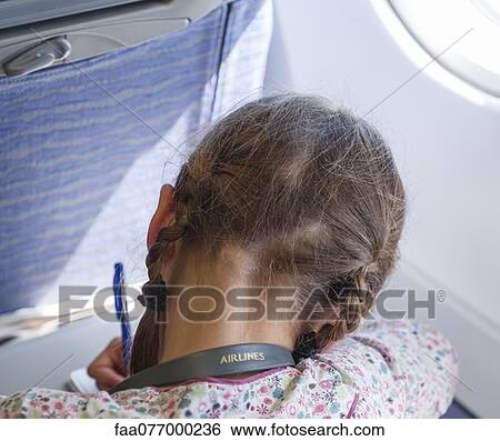Stock Photograph - Girl writing on airplane, rear view. Fotosearch