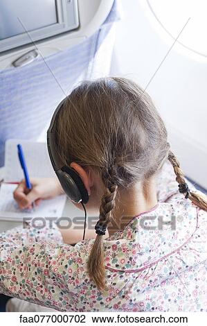 Stock Image - Girl writing on airplane. Fotosearch