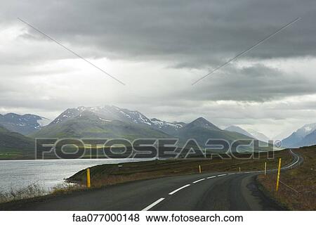 Stock Photo - Iceland, road through tranquil countryside with mountains in background. Fotosearch