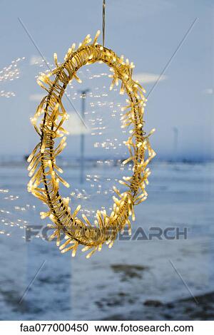 Stock Image - Illuminated Christmas decoration hanging in window. Fotosearch
