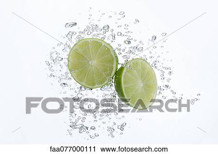 Stock Image - Lime halves submerged in sparkling water. Fotosearch