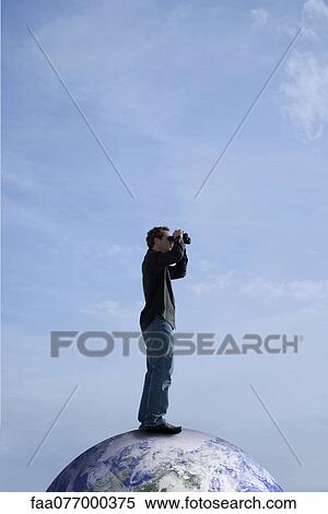 Stock Photography - Man standing on top of the world, looking through binoculars. Fotosearch