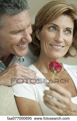 Stock Photography - Mature couple together, woman holding rose. Fotosearch
