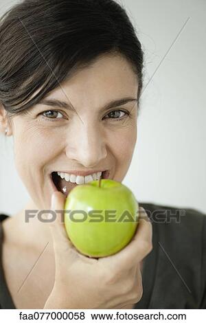 Stock Photo - Mid-adult woman biting into apple. Fotosearch