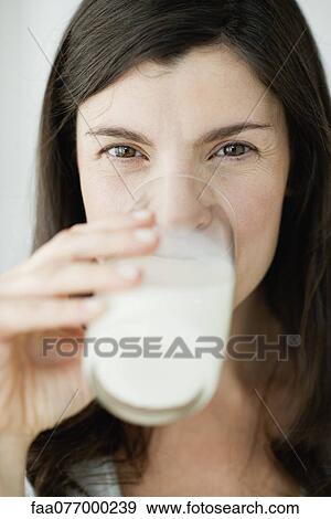 Stock Photo - Mid-adult woman drinking glass of milk. Fotosearch