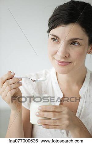 Mid-adult woman eating yogurt, portrait View Large Photo Image Stock Photograph - Mid-adult woman eating yogurt, portrait. Fotosearch