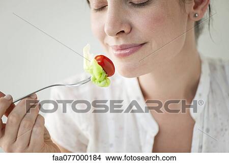 Mid-adult woman enjoying fresh vegetables View Large Photo Image Picture - Mid-adult woman enjoying fresh vegetables. Fotosearch