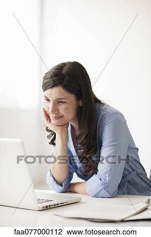 Stock Image - Mid-adult woman using laptop computer. Fotosearch