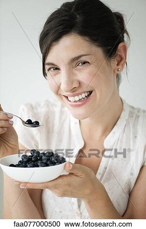 Stock Image - Mid-adult woman with bowl of blueberries. Fotosearch