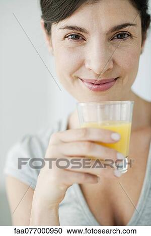 Stock Image - Mid-adult woman with glass of orange juice. Fotosearch
