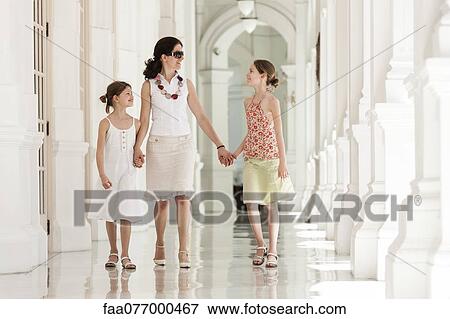 Stock Photo - Mother and daughter walking side by side holding hands. Fotosearch