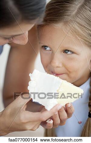 Picture - Mother feeding little girl cake. Fotosearch