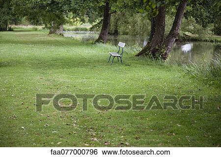 Stock Photograph - Park bench near water's edge. Fotosearch