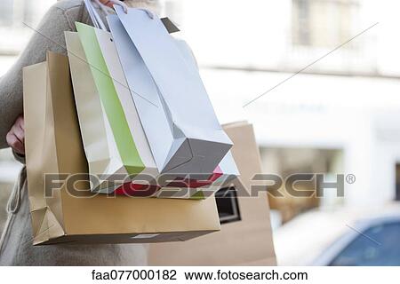 Stock Image - Person carrying shopping bags, cropped. Fotosearch