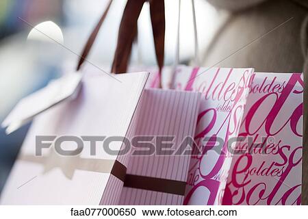 Stock Image - Person carrying shopping bags, cropped. Fotosearch