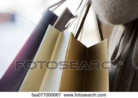 Stock Photo - Person carrying shopping bags, cropped. Fotosearch