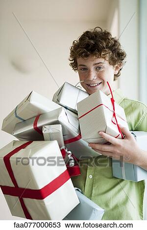Stock Image - Preteen boy holding armful of birthday gifts. Fotosearch