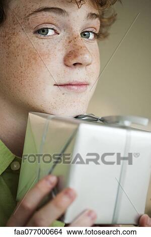 Preteen boy holding gift, portrait View Large Photo Image Picture - Preteen boy holding gift, portrait. Fotosearch