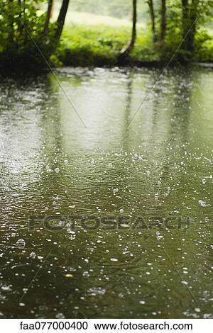 Stock Image - Raindrops on pond. Fotosearch