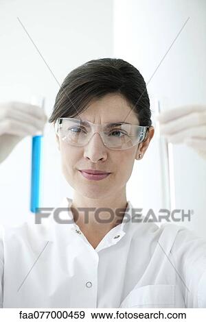 Scientist holding up test tubes containing liquid View Large Photo Image Stock Photo - Scientist holding up test tubes containing liquid. Fotosearch