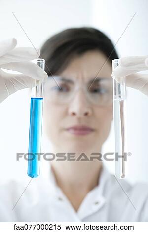 Stock Photography - Scientist holding up test tubes containing liquid. Fotosearch