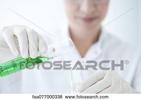 Stock Photo - Scientist pouring liquid from graduated cylinder to test tube. Fotosearch