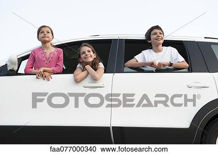 Stock Image - Siblings leaning out of car window, smiling, portrait. Fotosearch