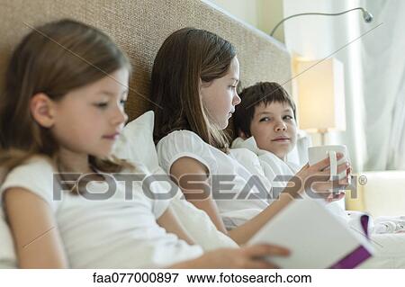 Stock Photo - Siblings relaxing on bed. Fotosearch
