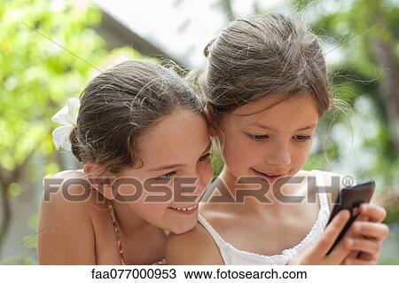 Sisters looking at cell phone together View Large Photo Image Stock Image - Sisters looking at cell phone together. Fotosearch