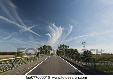 Whispy clouds and vapor trails in sky over bridge View Large Photo Image Stock Photography - Whispy clouds and vapor trails in sky over bridge. Fotosearch