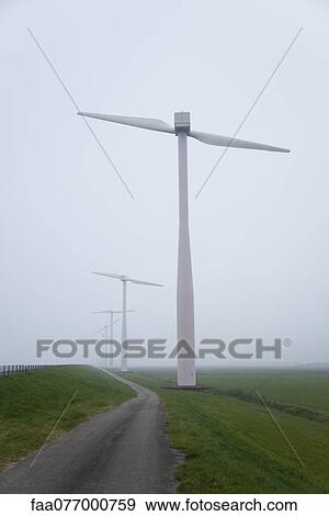 Stock Photo - Wind turbines along dirt road in field. Fotosearch
