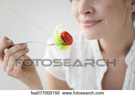 Stock Image - Woman eating salad, cropped. Fotosearch