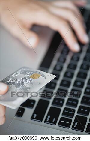 Woman holding credit card while using laptop computer, cropped View Large Photo Image Stock Image - Woman holding credit card while using laptop computer, cropped. Fotosearch