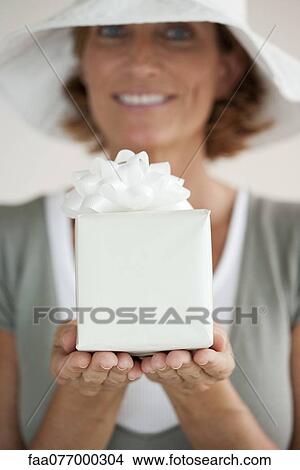 Picture - Woman holding out wrapped gift. Fotosearch