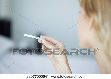 Stock Image - Woman holding pregnancy test, cropped. Fotosearch