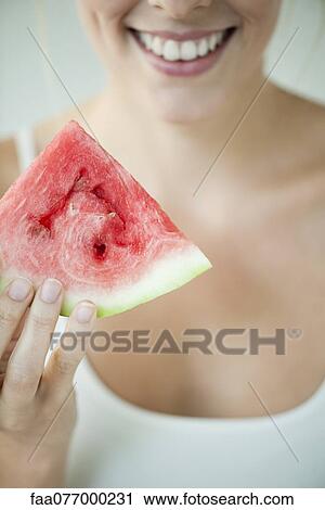 Stock Image - Woman holding slice of watermelon. Fotosearch