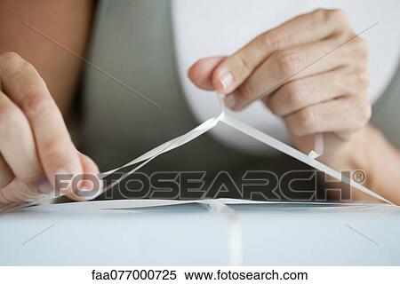 Stock Photography - Woman tying ribbon around gift, cropped. Fotosearch