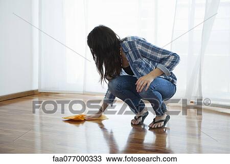 Stock Image - Woman wiping hardwood floor. Fotosearch