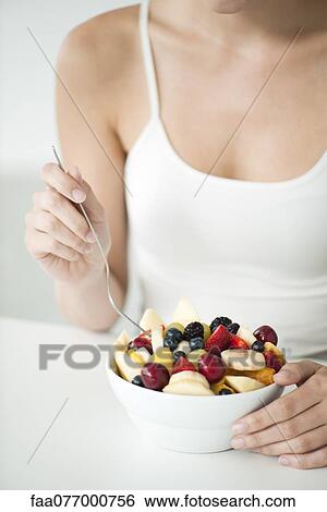 Stock Photograph - Woman with fruit bowl, mid section. Fotosearch