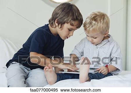 Young brothers playing with digital tablet View Large Photo Image Stock Photography - Young brothers playing with digital tablet. Fotosearch