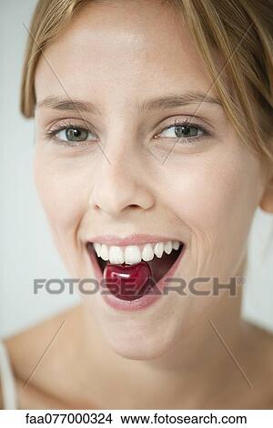 Picture - Young woman eating cherry. Fotosearch