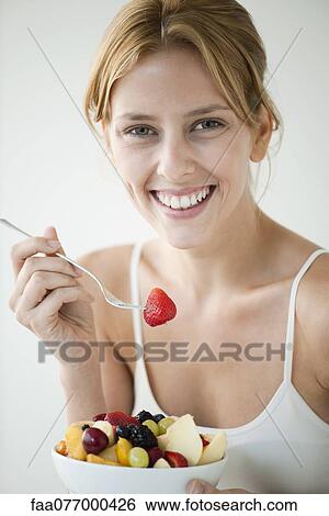 Young woman eating fruit salad, portrait View Large Photo Image Stock Photograph - Young woman eating fruit salad, portrait. Fotosearch