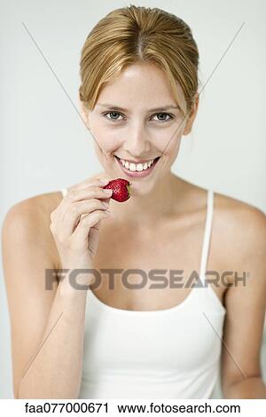 Young woman eating strawberry, portrait View Large Photo Image Stock Image - Young woman eating strawberry, portrait. Fotosearch
